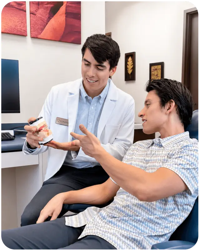 Dr. Martinez showing a patient a dental model in the treatment chair